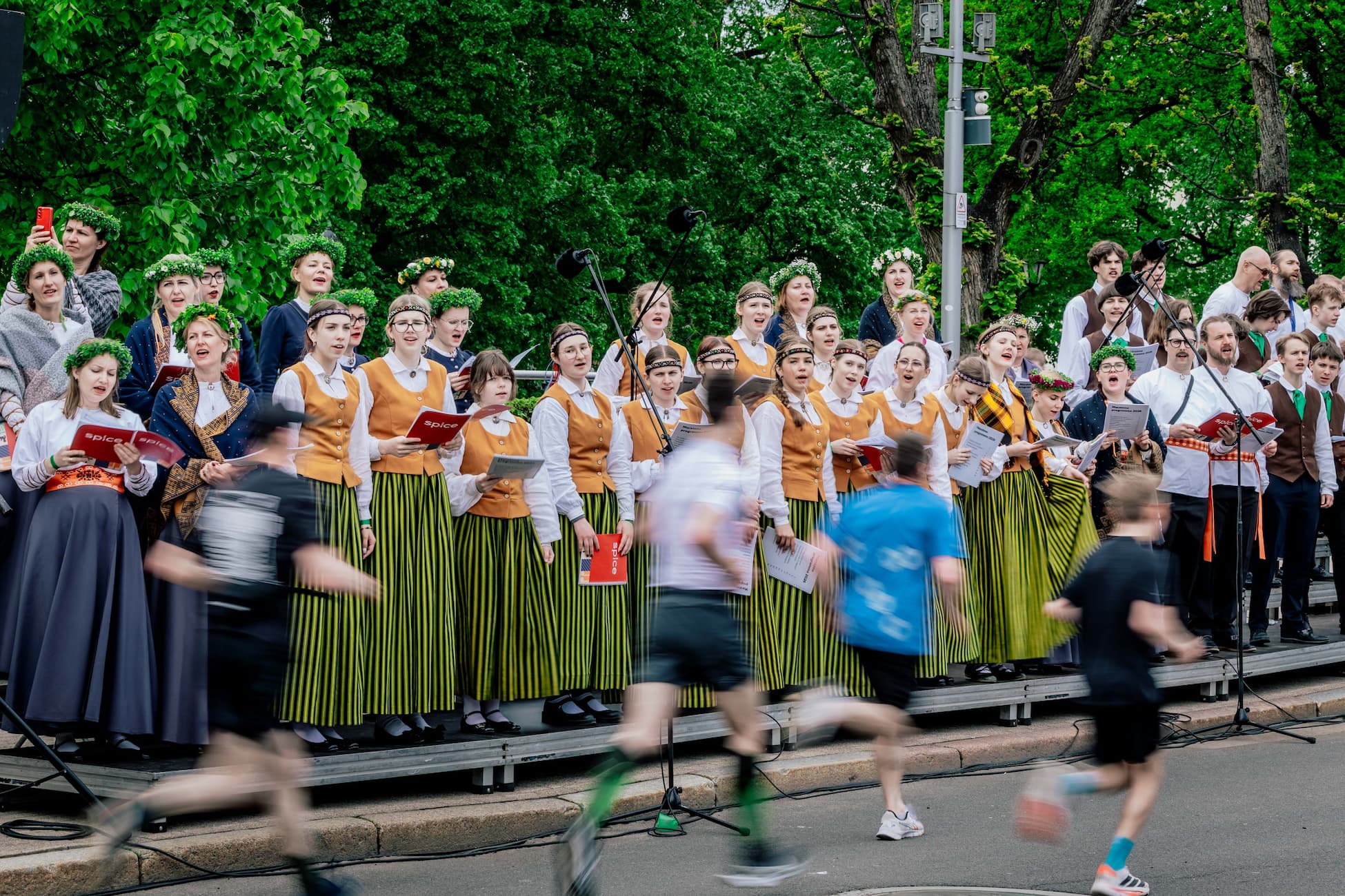 Runners passing a Latvian choir performing beside the course